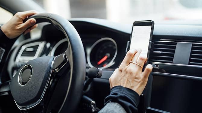 En kvinne som bruker telefonen sin i bilen for å se etter usikrede WiFi-nettverk.